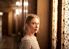 pexels-photo-1542085-1542085 Portrait of a woman in an elegant, warm-toned room with stained glass window. Artistic and serene.