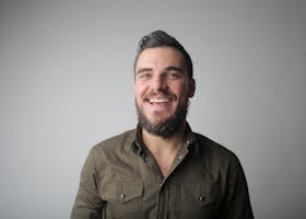 pexels-photo-3785079-3785079 Portrait of a bearded man smiling joyfully in a casual studio setting.