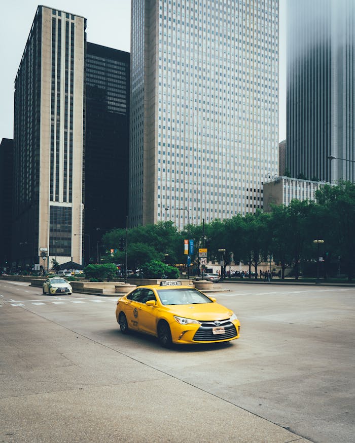 zipwp-image-1662160 A yellow taxi drives through the bustling streets of downtown Chicago, surrounded by skyscrapers.